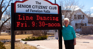 Senior standing by club sign
